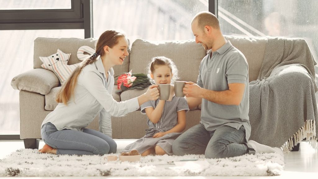A joyful family enjoying quality time and coffee in a bright living room, symbolizing love and togetherness.