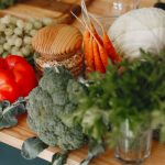 A vibrant display of fresh vegetables and fruits on a wooden board, including bell pepper, cabbage, and more.