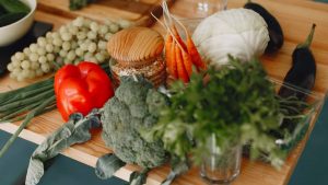 A vibrant display of fresh vegetables and fruits on a wooden board, including bell pepper, cabbage, and more.