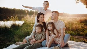 A family of five enjoying a serene picnic in a sunlit meadow during sunset.