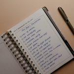 An open notebook on a brown background featuring handwritten New Year's resolutions.